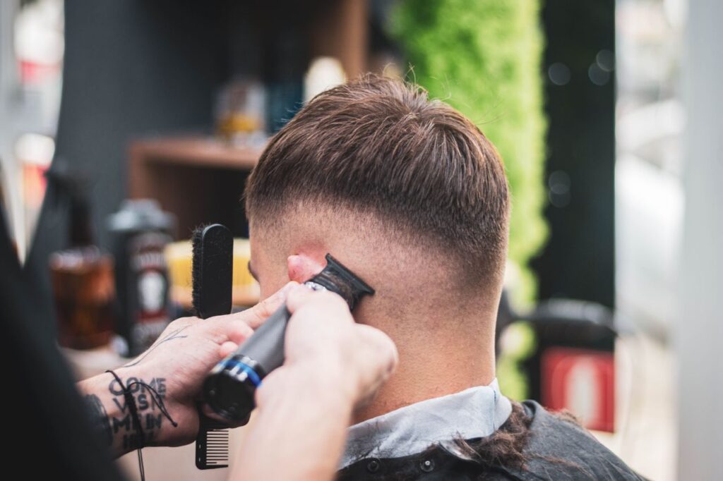 pexels-photo-34702982 A barber skillfully trims a young man's hair in a modern salon setting, showcasing expertise and precision.